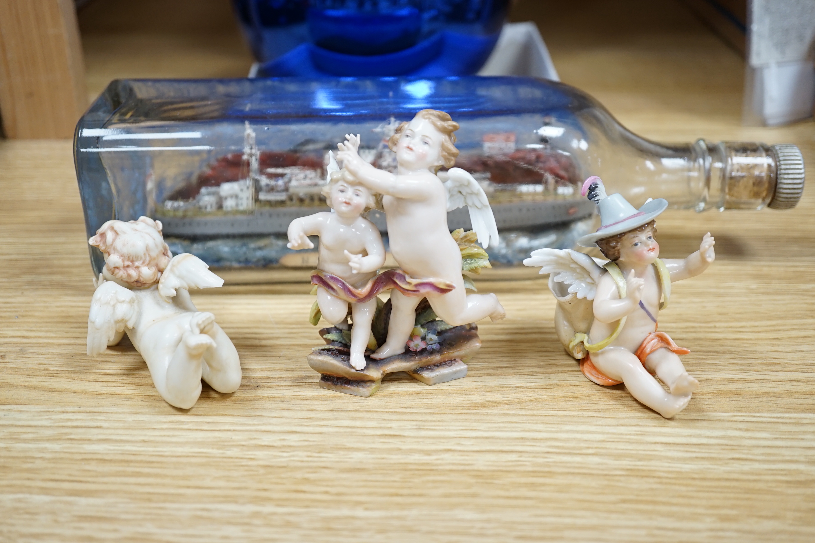 Ten sundry items including a small witch’s ball, three cherub figures with Meissen marks, a Continental bowl, four marble eggs, a Royal Navy ship in a bottle and another figure